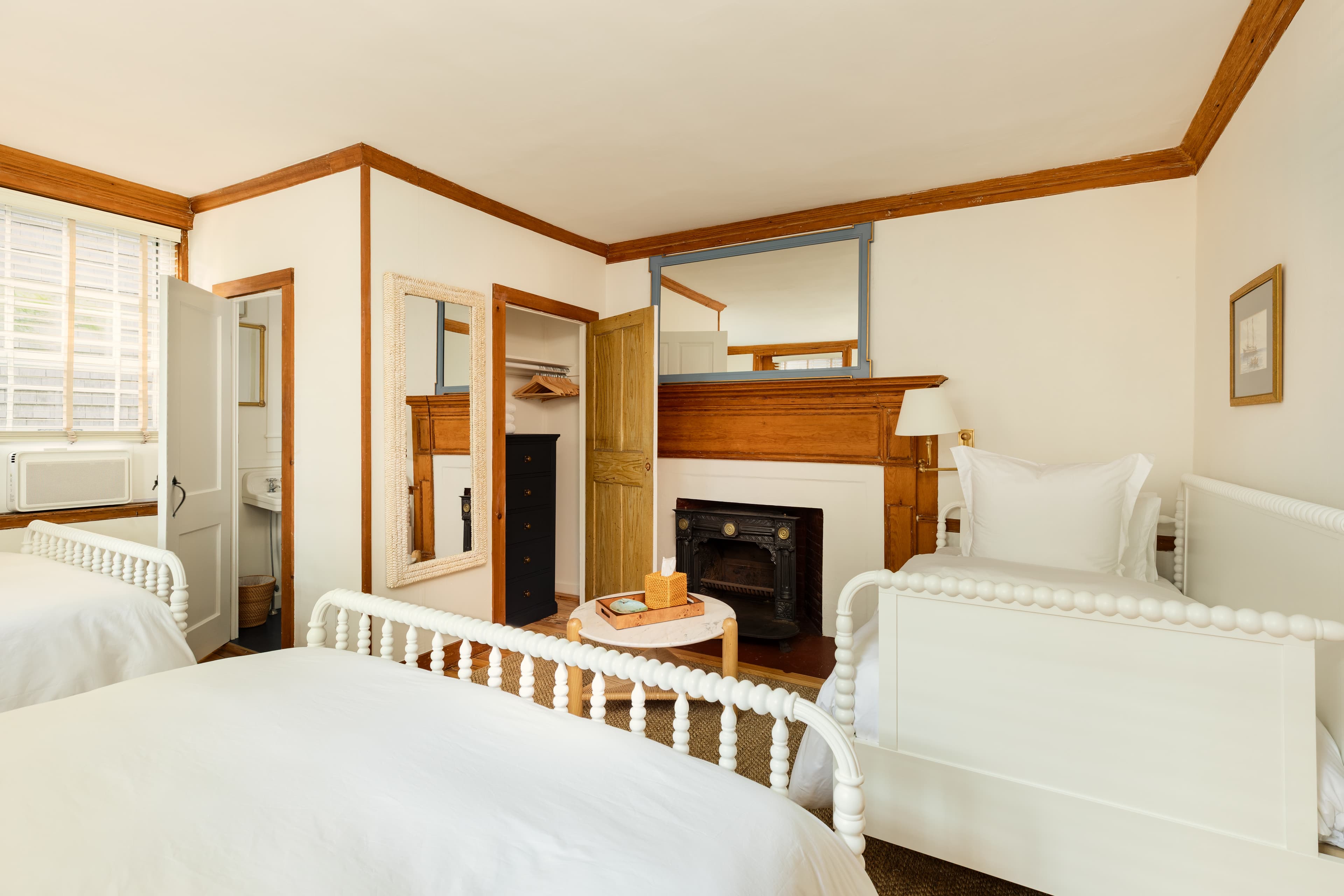 A sunlit room with two queen beds, a daybed, a cozy fireplace, and warm wooden accents, offering a comfortable and inviting atmosphere.