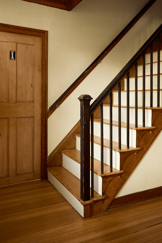 A wooden staircase leading to a door labeled "1" with a warm-toned interior.
